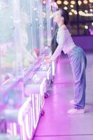 Young Woman Enjoying Claw Machine in Colorful Arcade Setting photo