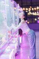 Young Woman Enjoying Vending Machine in Neon Setting with Plush Toys photo