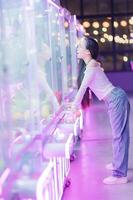 Young woman enjoys arcade game in colorful neon-lit environment photo