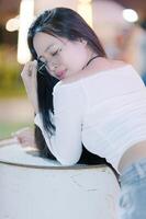 Young woman with glasses resting on a barrel in soft lighting photo
