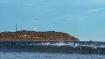 man i våtdräkt Försök till stå på surfingbräda medan ridning Vinka, men misslyckas och falls in i isig vattnen av arktisk hav mot bakgrund av oländig bergen täckt i tundra. video