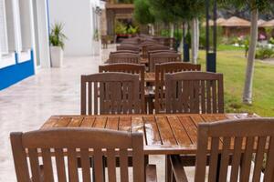 Series of empty wooden tables lined up in a garden setting after rain photo