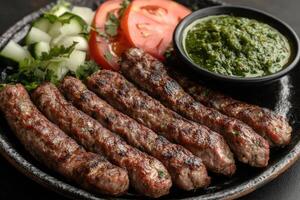 Barbecued kofta kebabs with green chutney and salad on skew.ers photo