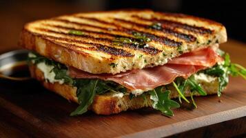 Delicious grilled panini with prosciutto, arugula, and balsamic glaze on wooden cutting board photo