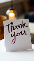 Thank you card placed elegantly on table with warm candlelight in background creating a cozy atmosphere photo