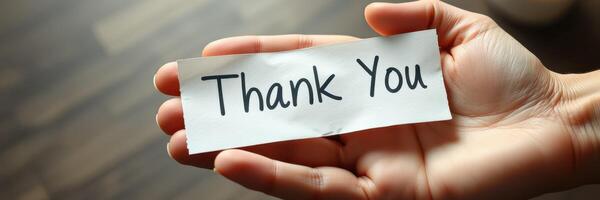 Hand holding a thank you note, conveying appreciation and gratitude during a sincere moment photo