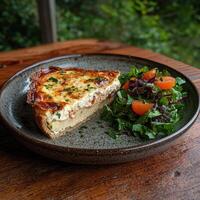 A slice of delicious quiche with a side salad on a rustic wooden table photo