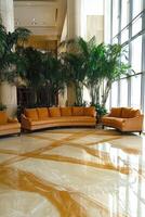 Luxury hotel lobby with orange couches and palm trees photo
