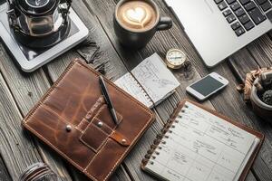 A laptop, coffee, notebook, and pen on a wooden table photo