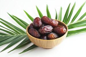 Dates in a bowl with palm leaves photo