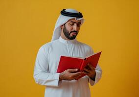 Arab man reading book on yellow background photo