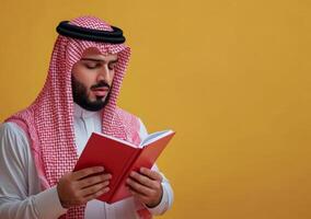Arab man reading book on yellow background photo