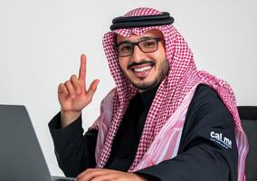 Smiling Man In Traditional Dress Gesturing With A Laptop photo