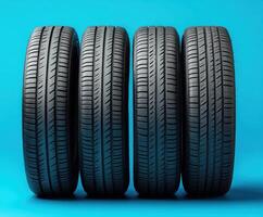Four new tires arranged in a row against a bright blue background, showcasing their tread patterns and design photo