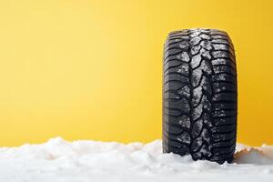 Snow-covered tire on bright yellow background highlighting winter performance and traction characteristics photo