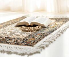 Prayer rug with open book and prayer beads on a sunny surface near window photo