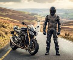 Motorcyclist in black gear stands next to sports bike on winding road through scenic countryside at sunset photo