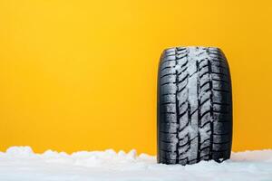 Snow-covered tire against a vibrant yellow background showcasing winter conditions and seasonal changes photo