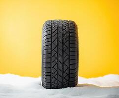 Snow-covered tire against a bright yellow background highlighting winter readiness and vehicle safety photo