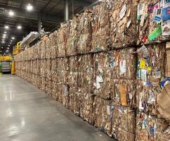Large bales of recycled paper stacked in a processing facility for sorting and repurposing photo