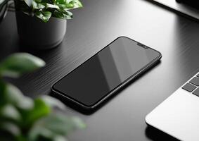 Smartphone lying on desk with plants and laptop in home office setup photo