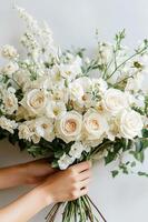 Florist arranging white and cream roses and delphiniums bouquet photo