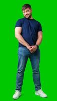 Man standing with a thoughtful expression in a casual outfit against a green background photo