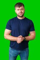 Man standing with a thoughtful expression in a casual outfit against a green background photo