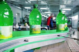 Bottling process of soft drinks in a factory during daytime with green plastic bottles on a conveyor belt photo