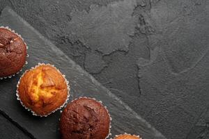 Freshly baked muffins displayed on a dark slate surface, showcasing a variety of flavors and textures inviting a delicious treat photo