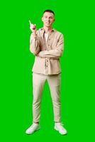 Young Man Pointing Upward While Smiling Against a Bright Green Background photo