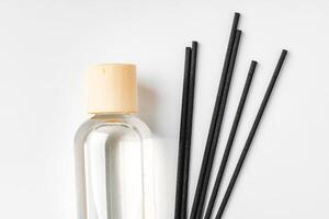 A minimalist display of essential oil and black diffuser sticks on a clean white background photo