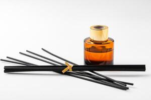 A minimalist display of essential oil and black diffuser sticks on a clean white background photo