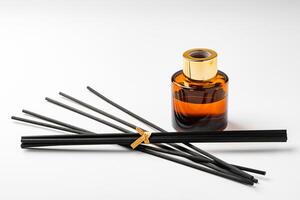 A minimalist display of essential oil and black diffuser sticks on a clean white background photo