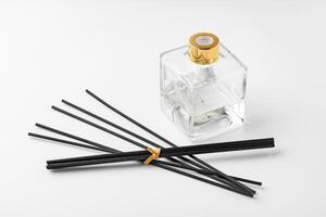 A minimalist display of essential oil and black diffuser sticks on a clean white background photo