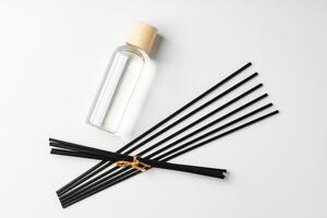 A minimalist display of essential oil and black diffuser sticks on a clean white background photo