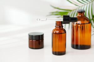 Collection of Amber Glass Bottles and Jars for Essential Oils on a White Surface photo