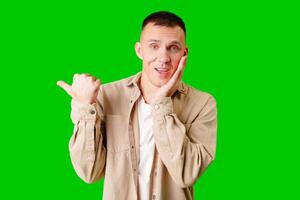 Man Wearing Casual T-Shirt Pointing Against Bright Green Background photo