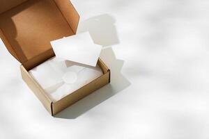 Brown cardboard box with a blank envelope on a light background in a well-lit setting photo