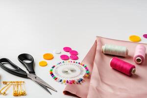 Crafting supplies arranged on a table with fabric, thread and buttons during daytime photo