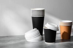 Stack of coffee cups in various colors with lids on a gray surface photo