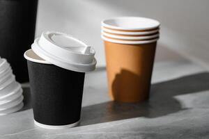 Stack of coffee cups in various colors with lids on a gray surface photo