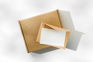 Brown cardboard box with a blank envelope on a light background in a well-lit setting photo