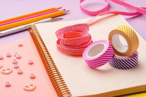 Scissors and decorative tape on colorful craft paper in a bright workspace photo
