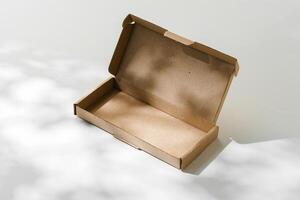 Open cardboard box on a reflective surface with soft shadows photo