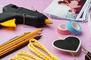 Crafting supplies arranged on a pink background, including glue gun, scissors, and decorative items for DIY projects photo
