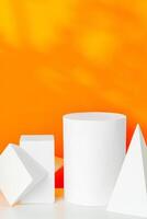 White geometric shapes on a vibrant orange background with soft shadows in a well-lit indoor setting photo