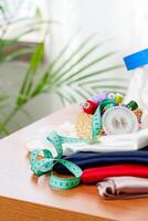 Crafting supplies arranged on a wooden table with colorful threads, measuring tape, and fabric in a well-lit workspace photo