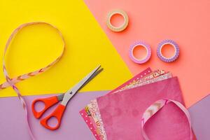 Scissors and decorative tape on colorful craft paper in a bright workspace photo