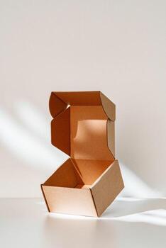 An open cardboard box rests on a bright white surface with soft shadows highlighting its edges and structure in natural light photo